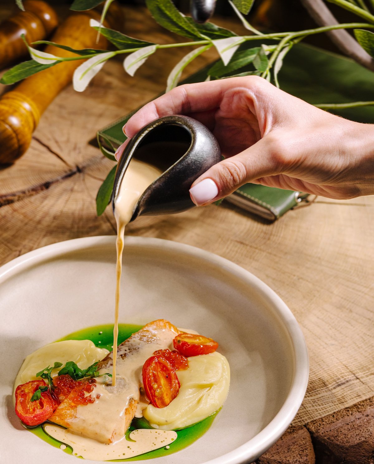 Plated salmon dish with sauce being poured