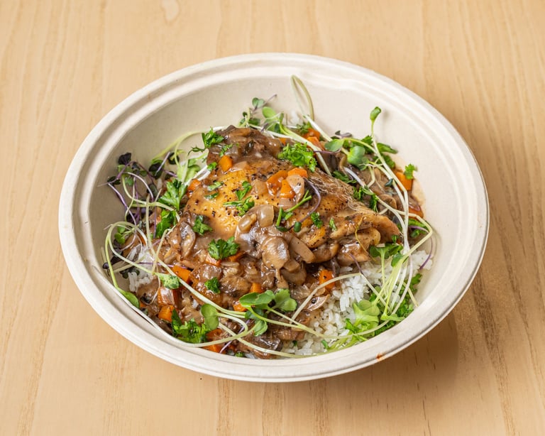 Asian noodle bowl with glazed meat, fresh microgreens, and sprouts in white container on wooden surface