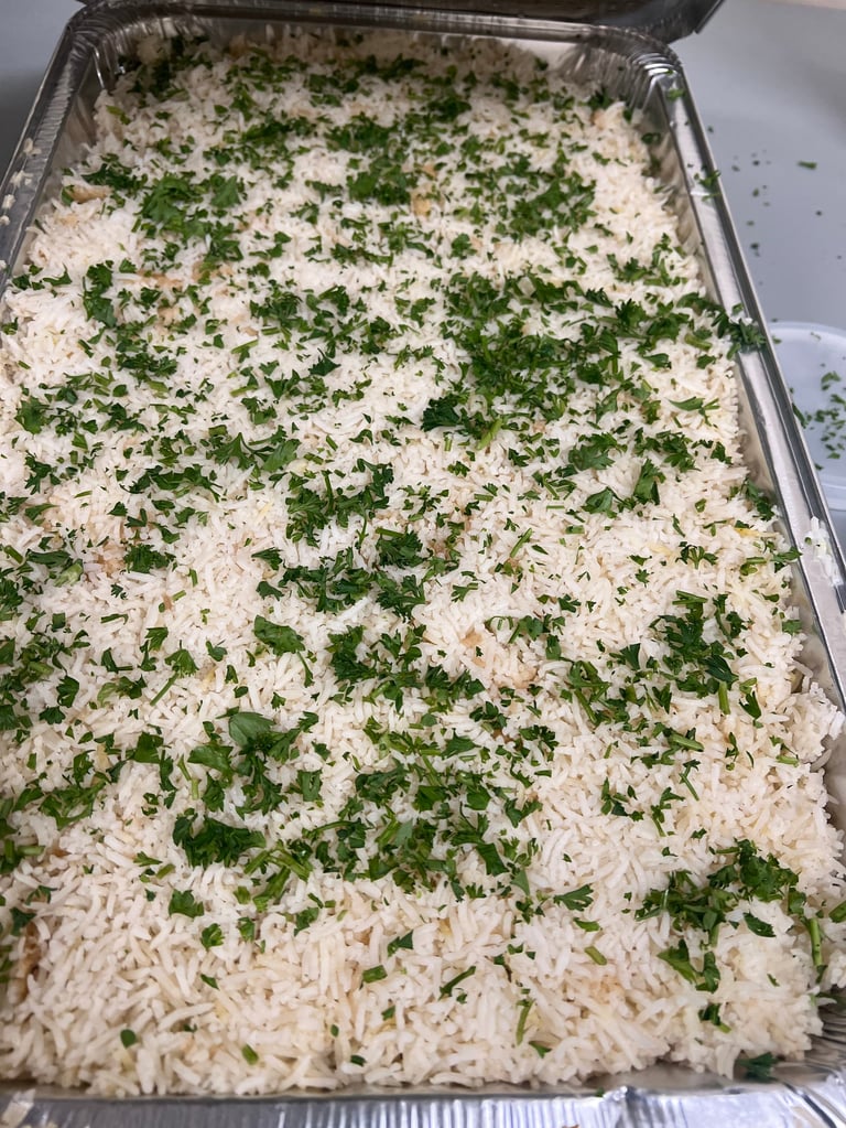 Aluminum tray of white rice garnished with fresh green herbs