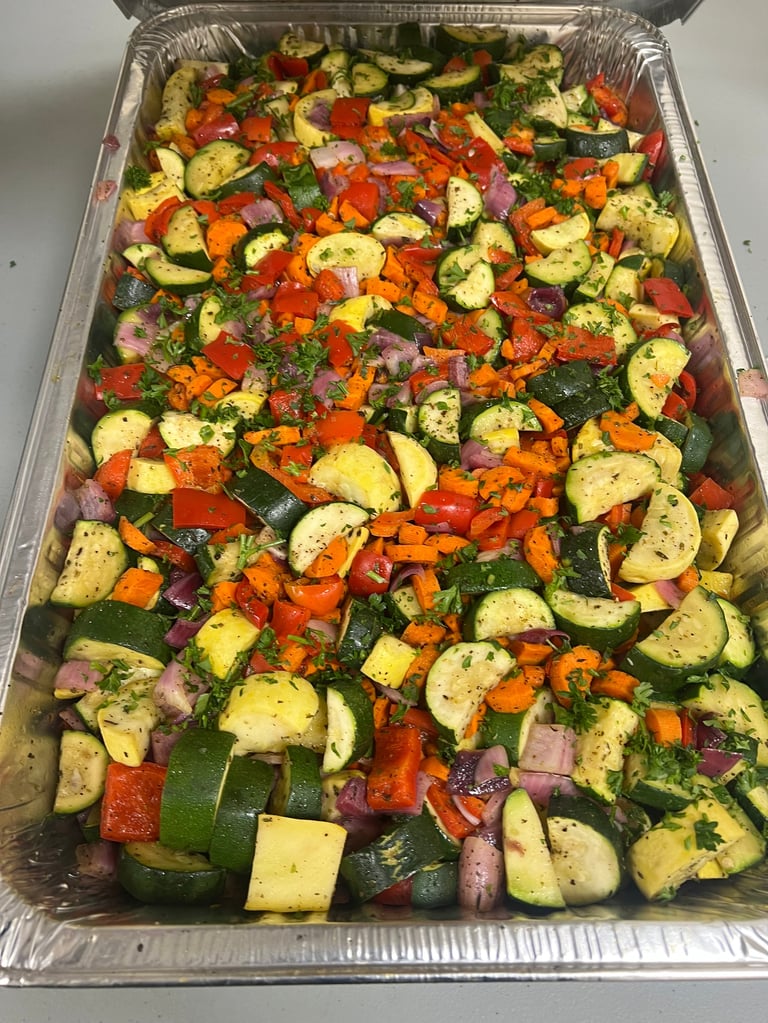Roasted vegetables in aluminum tray including sliced zucchini, bell peppers, and ham pieces