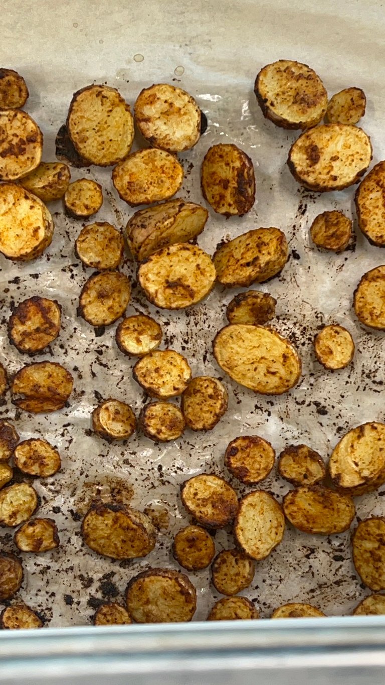 Roasted potato slices with seasoning on parchment paper on a baking sheet
